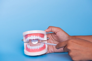Different dental tools for demonstration patient.Model tooth model, mirror, sickle probe, dental floss, surgical forceps and toothbrush on blue background.Dentist healthcare education concept.
