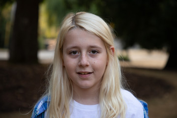 Fototapeta premium Close up of boy with long blond hair walking in park