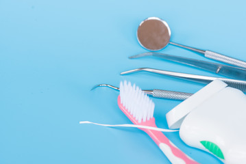 Different dental tools for demonstration patient.Model tooth model, mirror, sickle probe, dental floss, surgical forceps and toothbrush on blue background.Dentist healthcare education concept.