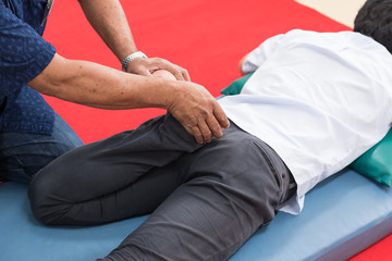 Young working man lying down while enjoying the stretching foot and leg techniques of a professional Thai massage in the spa and wellness center. physical therapy.Muscular treatment office syndrome.