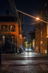 Dark and scary vintage cobblestone brick city alley with car at night in Chicago