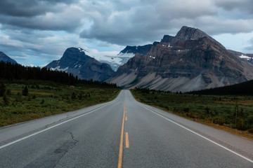 Scenic road in the Canadian Rockies during a vibrant cloudy sunset. Taken in Icefields Parkway, Banff National Park, Alberta, Canada.