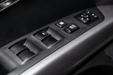 Close-up of the side door buttons: window adjustment buttons, door lock. modern car interior: parts, buttons, knobs.
