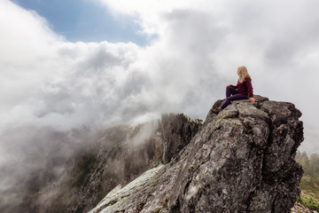 Adventurous Girl on top of a rugged rocky mountain during a cloudy summer morning. Taken on Crown...