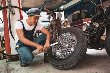 Fototapeta na wymiar Mechanical technician man maintenance and repair motorbike at workshop, vintage moto style