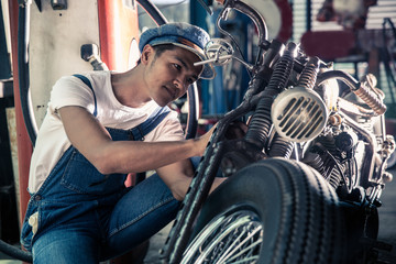 Mechanical technician man maintenance and repair motorbike at workshop, vintage moto style