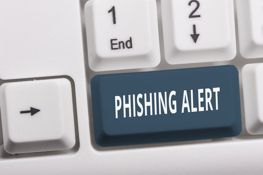 Writing note showing Phishing Alert. Business concept for aware to fraudulent attempt to obtain sensitive information White pc keyboard with note paper above the white background