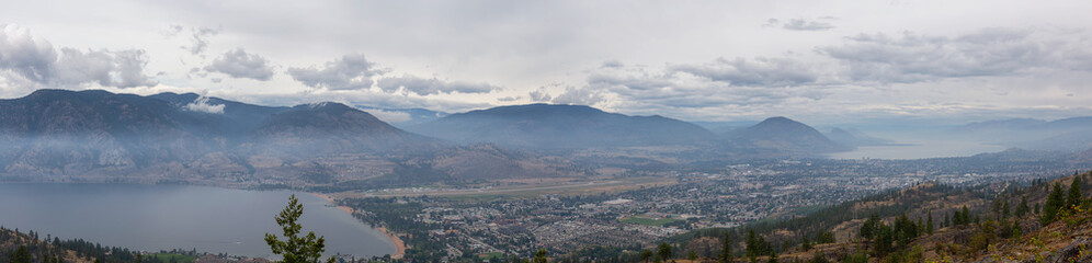 Fototapeta na wymiar Panoramic view of Penticton City during a cloudy and smokey summer morning. Taken in Skaha Bluffs Provincial Park, British Columbia, Canada.