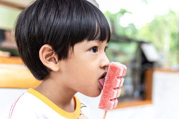 Asian cute little boy eating strawberry ice cream stick