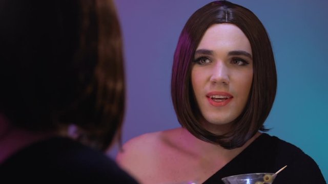 Smiling travesti drinking cocktail admiring mirror reflection, night club relax