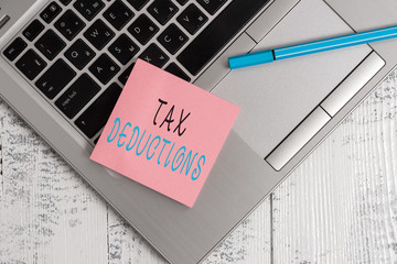 Conceptual hand writing showing Tax Deductions. Concept meaning an amount or cost that subtracted from someone s is income Open slim metallic laptop blank sticky pad pen lying vintage table