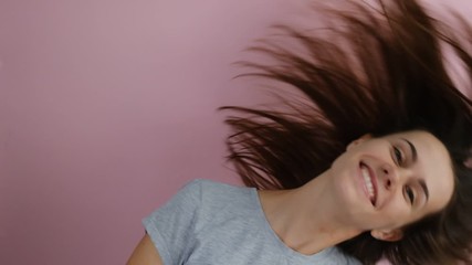 Close up of a young pretty girl with long hair shaking her head isolated over pink background. People sincere emotions lifestyle.