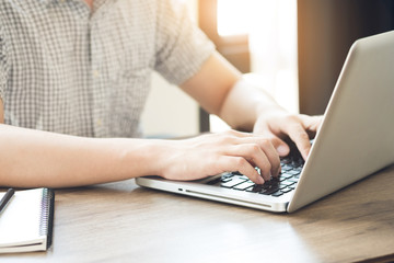 Young college student is typing on laptop keyboard. Internet research concept.