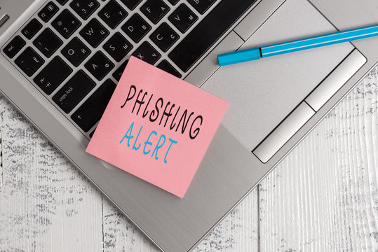 Conceptual hand writing showing Phishing Alert. Concept meaning aware to fraudulent attempt to obtain sensitive information Open slim metallic laptop blank sticky pad pen lying vintage table