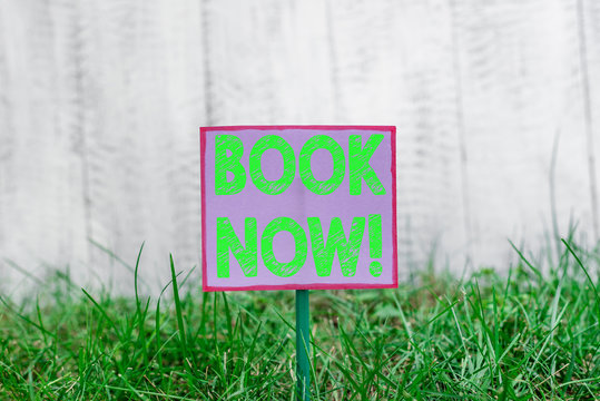 Text sign showing Book Now. Business photo text guaranteed to have place because you have already purchased it Plain empty paper attached to a stick and placed in the green grassy land