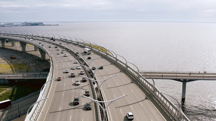 Fototapeta premium A smooth aerial flight, a flight over a bridge standing over a river on which cars ride. 4k.