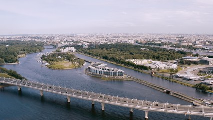 Obraz premium A smooth aerial flight, a flight over a bridge standing over a river on which cars ride. 4k.