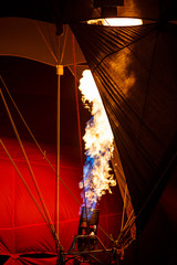 The burners on a hot air balloon firing up, sending a burst of ignited gas  in balloons festival night