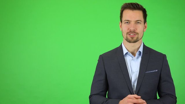A young handsome businessman talks to the camera with a smile - green screen studio