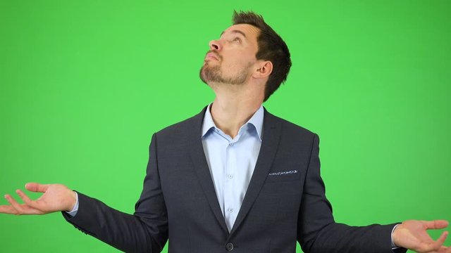 A young handsome businessman throws out his hands and looks around helplessly - green screen studio