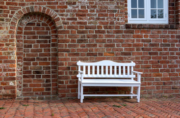 In front of an old brick church stands a small wooden bench