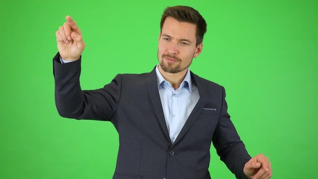 A businessman smiles at the camera and holds a picture in front of himself, he enlarges it with his fingers, holds, then pushes it to the side and out of the frame, continues smiling - green sreen  