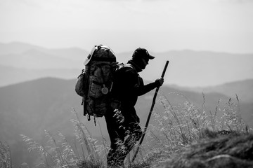 Traveler with backpack and mountain panorama. Hiker with backpack standing on top of a mountain.