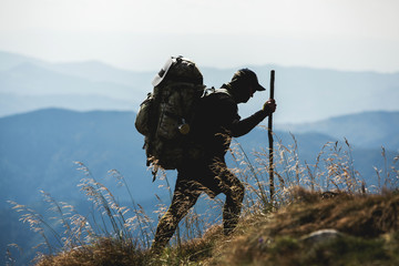 Traveler with backpack and mountain panorama. Hiker with backpack standing on top of a mountain.