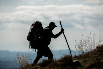 Traveler with backpack and mountain panorama. Hiker with backpack standing on top of a mountain.