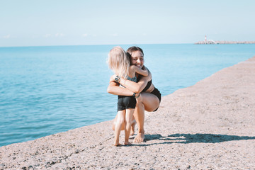 Fototapeta premium Young fit woman mom with little cute girl exercising on beach together, healthy lifestyle
