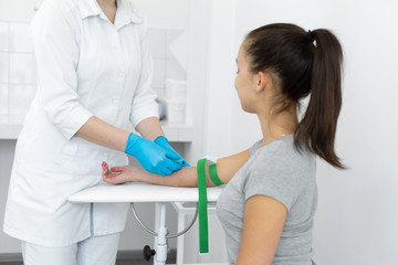 a nurse in the clinic inserts a catheter into a vein for blood testing for a young girl