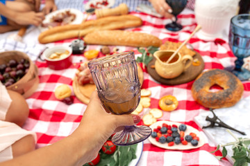 Hold glass with juice at picnic blanket background