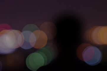 Blurred shadow of a person at night with colorful bokeh light.