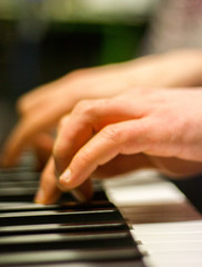 Fototapeta na wymiar Le mani di un giovane ragazzo suonano una tastiera in una sala prove