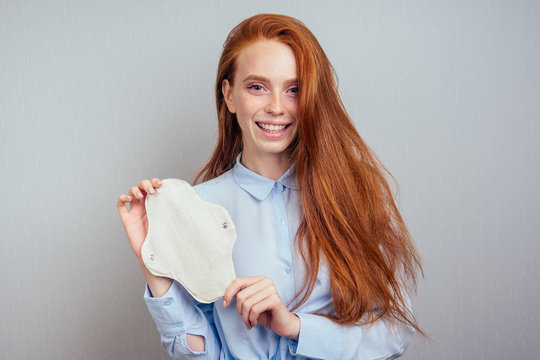 redhaired ginger long hair woman holding eco-friendly organic gaskets made of bio-cotton and disposable tampon.making choice.