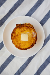 Homemade corn meal Johnny cakes with butter on a white plate, top view. Flat lay, overhead, from above. Close-up.