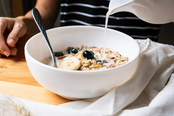 Healthy breakfast. Fresh granola, muesli with milk , bluberries and banana on wooden background.