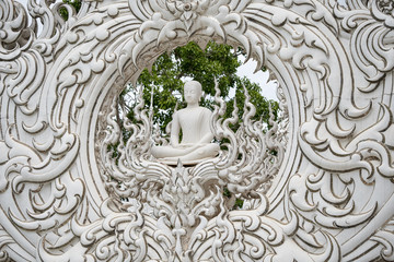 statue of a white monk inside a circle of ornaments, in the temple of Chiang Rai, northern Thailand