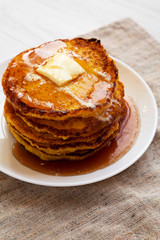 Homemade Cornmeal Johnnycakes with butter and maple syrup on a white plate, low angle view. Close-up.