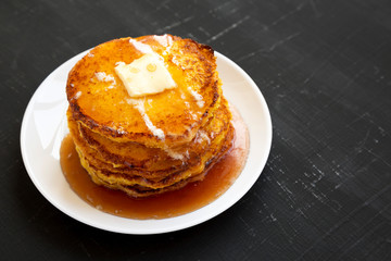 Homemade corn meal Johnny cakes on a white plate on a black background, side view. Copy space.