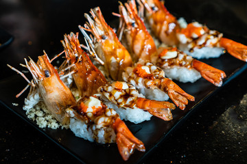 Ebi shrimp nigiri sushi on black ceramic plate in Japanese restaurant.
