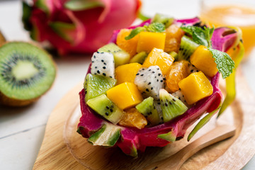 tropical fruits salad served in a half of  dragon fruit