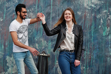 Cool multiracial couple posing against wall and dancing.