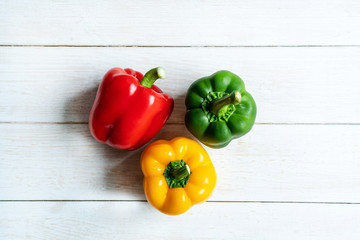 Fresh three color sweet peppers on white  wooden