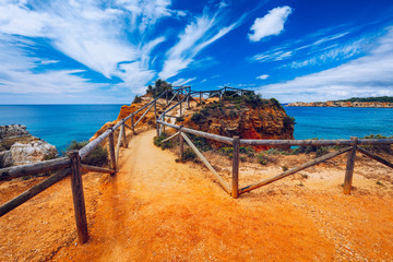 Coastal trail of Portimao on the Algarve coast. Overlooking the cliffs and ocean from the hiking trails in Portimao, Algarve, Portugal. Beautiful coast with wooden path in Portimao, Algarve, Portugal.