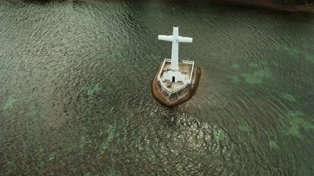 Catholic cross in sunken cemetery in the sea at sunset, aerial drone. Large crucafix marking the underwater sunken cemetary, Camiguin Island Philippines.
