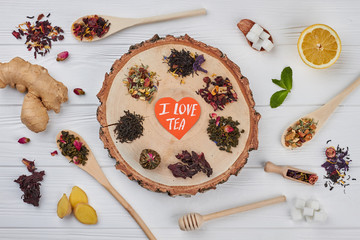 I love tea concept. Different kinds of dry tea on wooden background, flat lay.