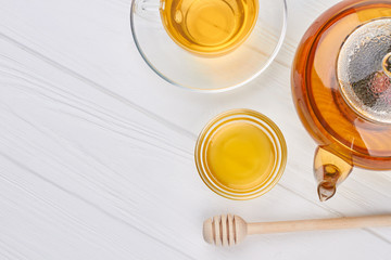 Teapot, honey and cup of tea. Composition with healthy drink on white wooden background.