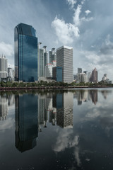 Skyline of Bangkok with Water or Lake in the foreground and big Clouds in the Sky