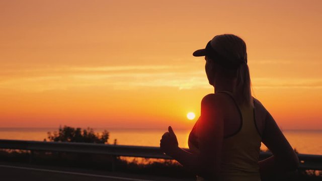 Athletic young woman jogging near the sea where the sun sets. Healthy lifestyle